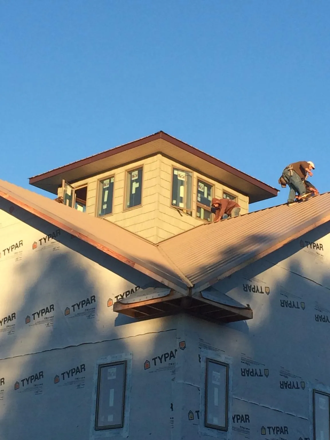 Roofers working around a rooftop cupola on a new metal roof at sunset — Roof Waterproofing in Dalton by Roofing Brothers